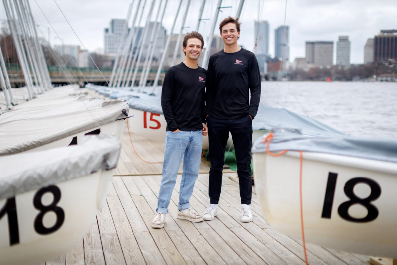Justin (left) and Mitchell Callahan ’26 at the Harvard Sailing Center along the Charles River.