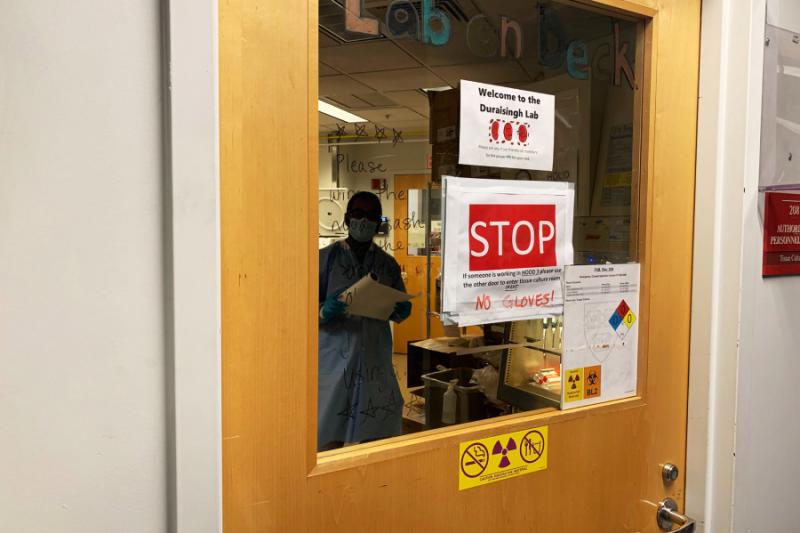 Research associate Aditya Paul works in the Duraisingh Lab, where signs illustrate new safety protocols.