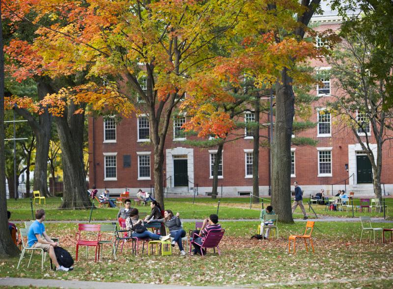 Image of students sitting on grass in front of building 