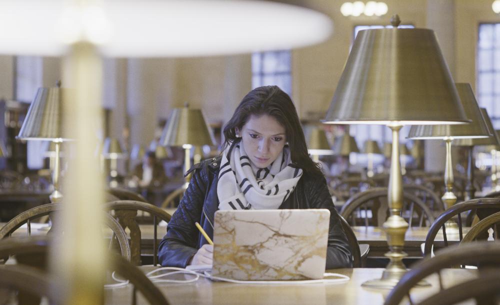 Female student working at a laptop in Widener library 