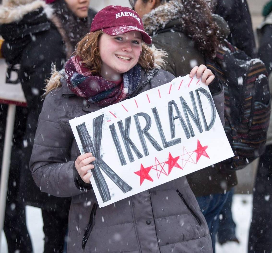 student holding sign that says "Kirkland" for Kirkland House on Housing Day 