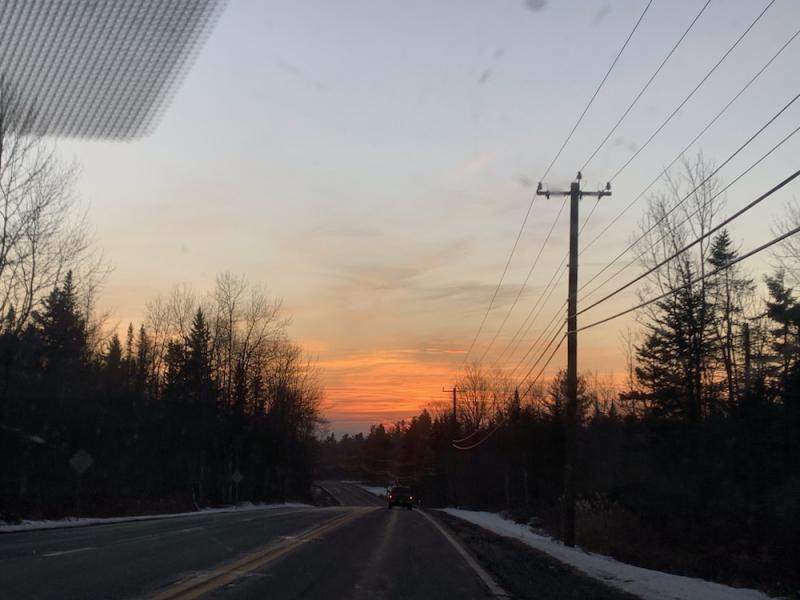 view out the car window of the sunset at the end of a long country road 