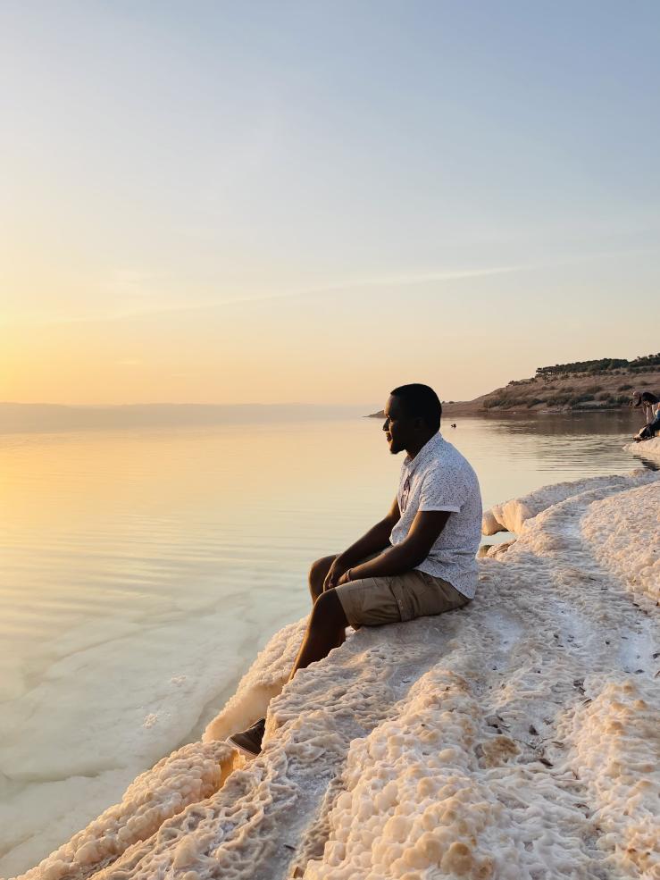 A photo of the writer sitting by the shores of the Dead Sea