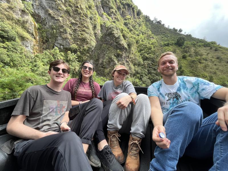 A picture of author and three friends sitting together with mountain in the background