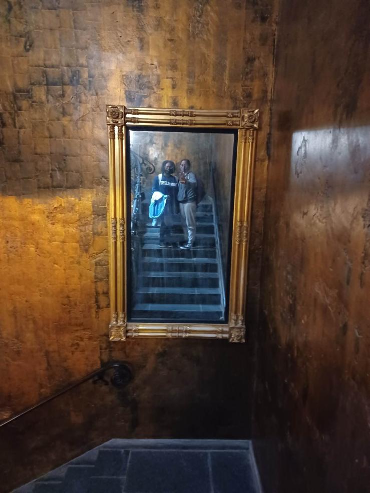 Author and a friend posing in front of a distorted mirror with a gold frame