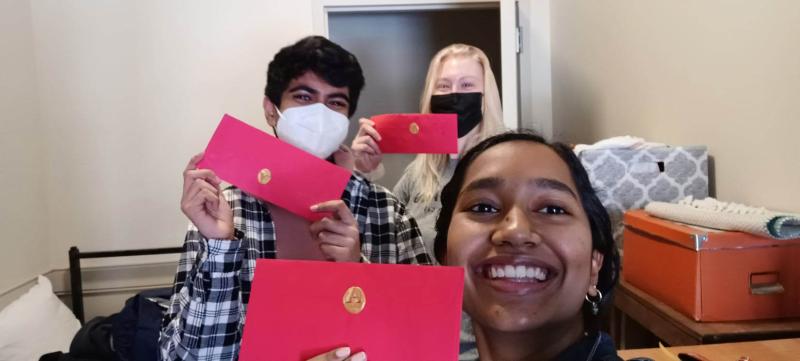 A picture of me and my friends holding up a red adams envelope