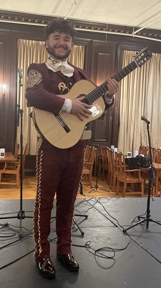 A mariachi performer standing with their guitar