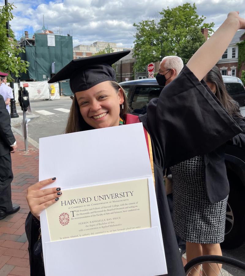 Harvard Grad Perrin holding her diploma in regalia outside of Claverly
