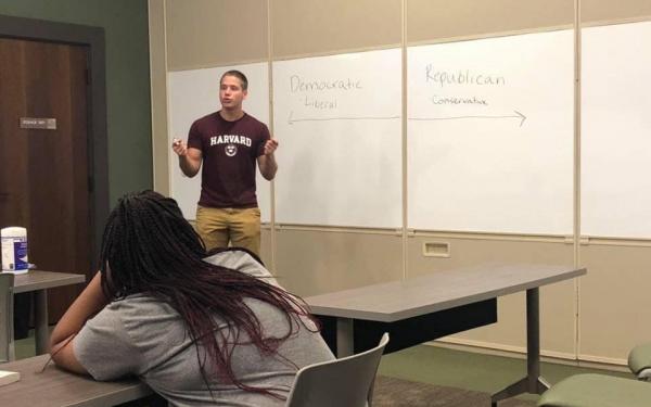 Student lecturing in front of a white board
