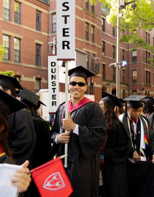 Students walking through Harvard Yard in caps and gowns. 