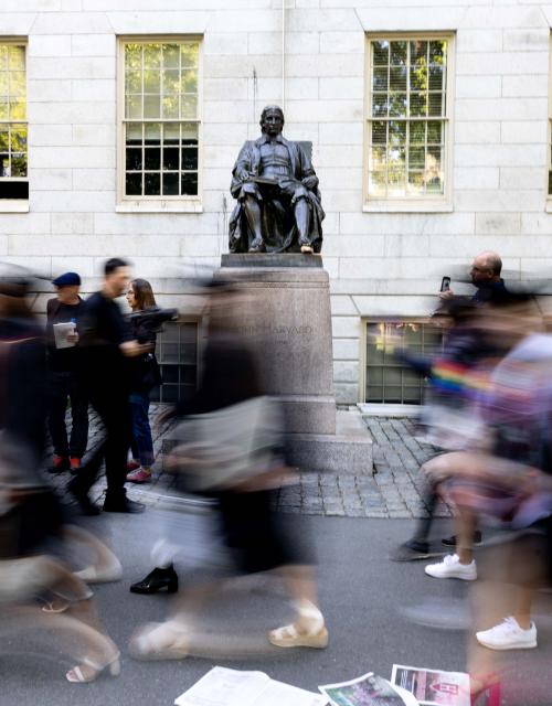 Students walking past the John Harvard statue