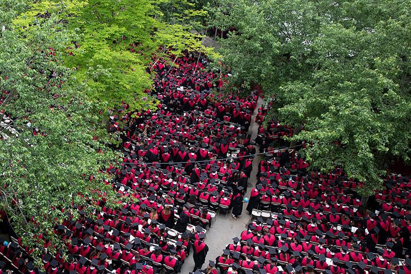 view from above of graduates sitting in Harvard Yard during commencement