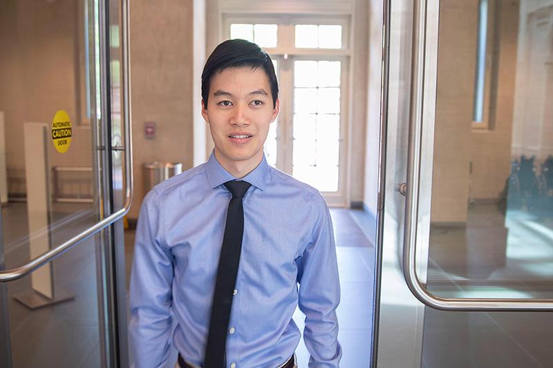 Michael Chen &#039;20 standing in a doorway smiling at he camera.