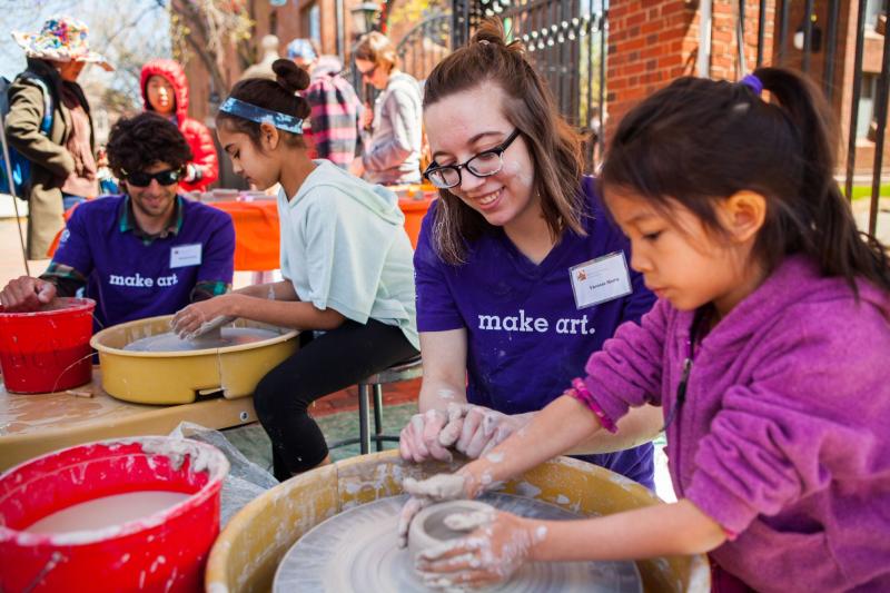 ARTS FIRST volunteer helping girl make pottery