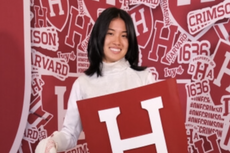 Cynthia Liu posing with Harvard crest in fencing uniform