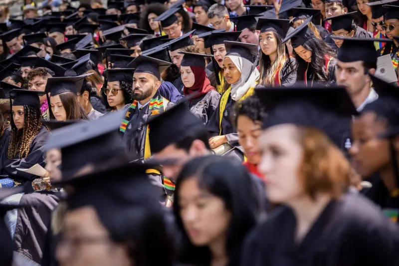 graduates in caps and gowns in seats on commencemnent