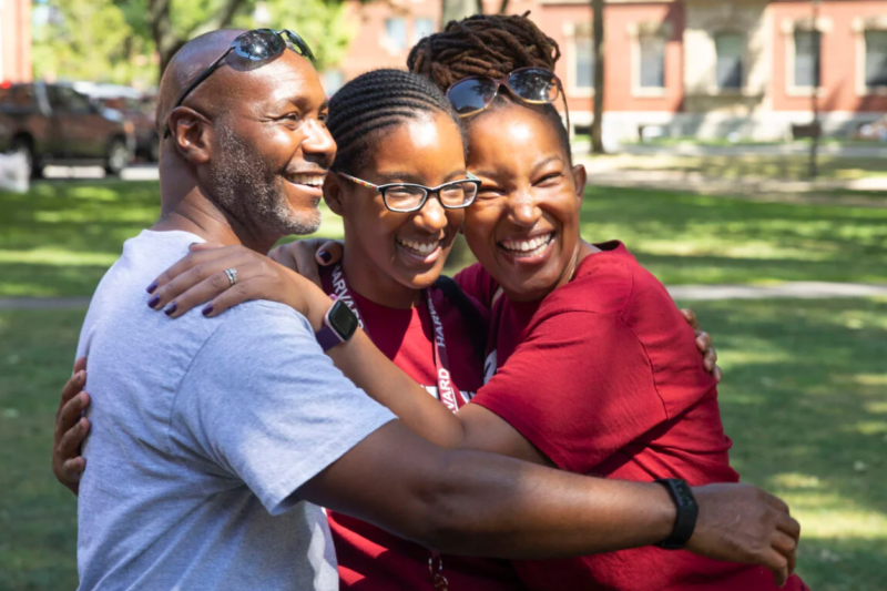 Lulu August ’26 (center) is hugged by her proud parents, Kakuri and Agnes, during first-year move-in last August in Harvard Yard. Photos by Kris Snibbe/Harvard Staff Photographer