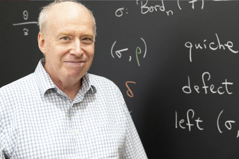 Professor Dan Freed standing in front of a chalk board covered in math symbols and equations.
