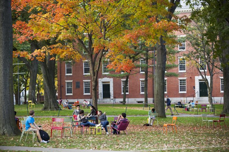 Image of students sitting on grass in front of building 