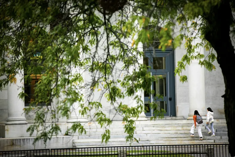 Students walk up set of stairs outside building 