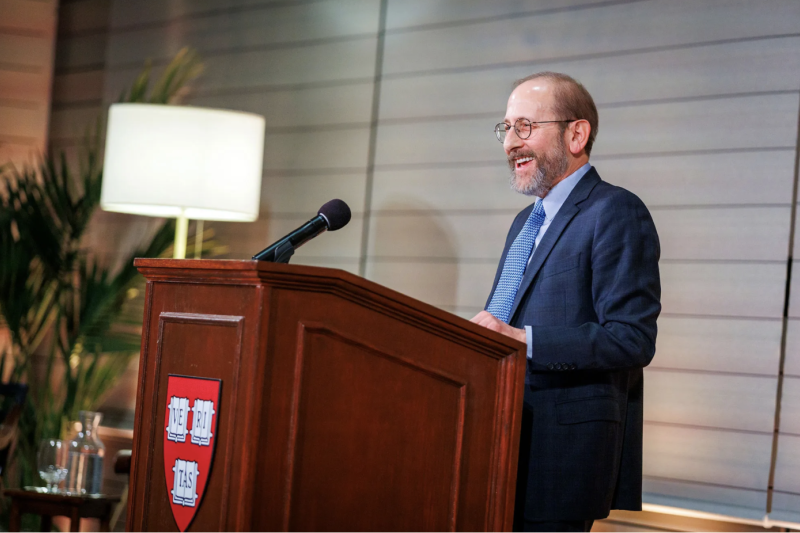 Alan Garber stands behind a podium with the Harvard Shield 