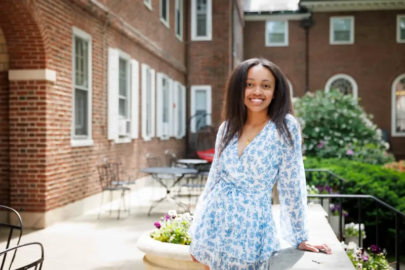Sophia Scott, Class of 2025, smiles and poses in a white and blue dress at Harvard College.