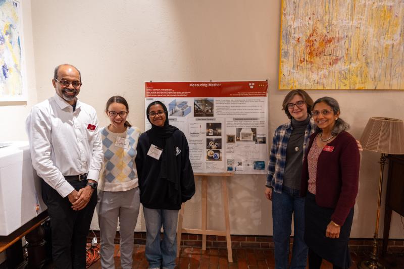 The Measure Mather team smile for a photo together next to a posterboard explaining their project.