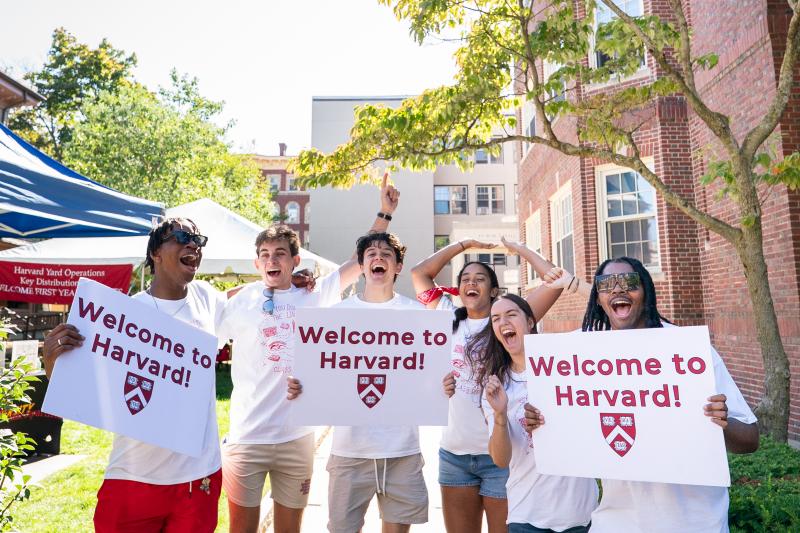 A group of Harvard College students cheer while holding up signs to welcome the incoming class.