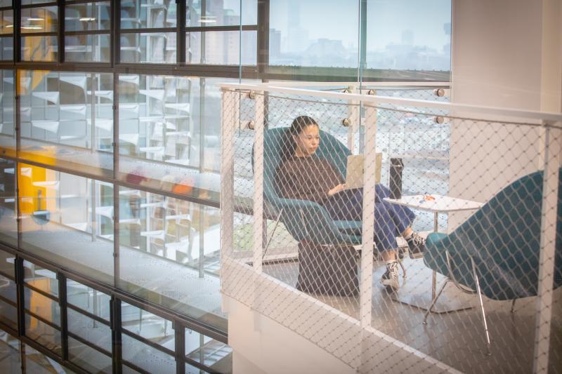 A young female student studying alone in a sectioned off cubicle overhang.