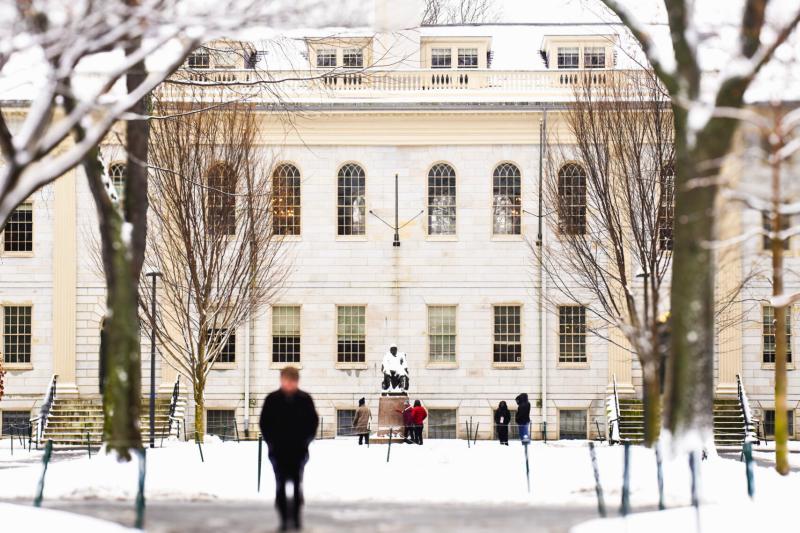 A winter landscape showing Harvard's University Hall framed by snow-covered trees.