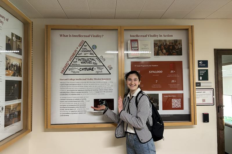 Ari standing next to the Intellectual Vitality display at Lamont Library, which she is a part of.