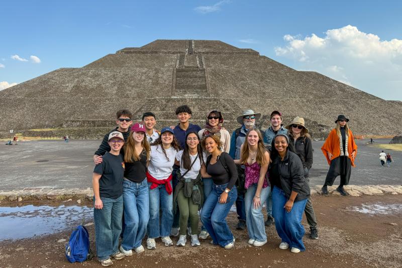 A group of students smiling in front of pyramids of Teotihuacan in Mexico.