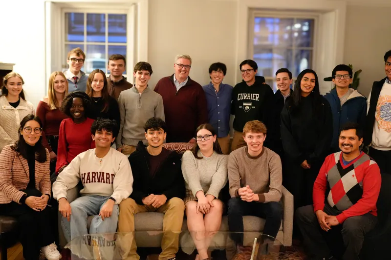 Large group of students and adults pose together in a living room.