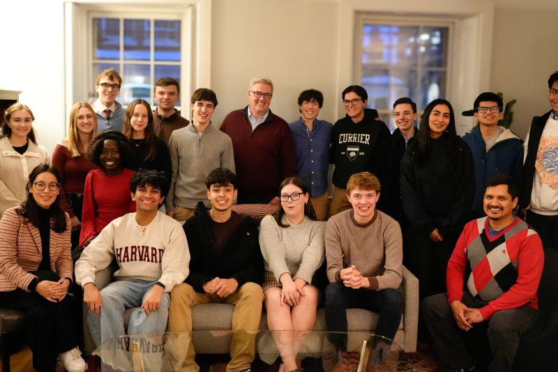 Large group of students and adults pose together in a living room.