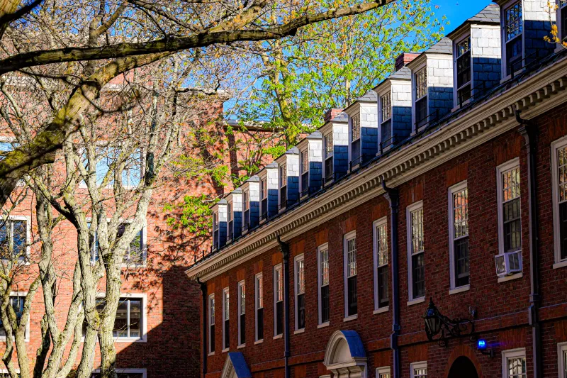 A close-up view of a historic red brick dormitory with slate-shingled dormer windows.