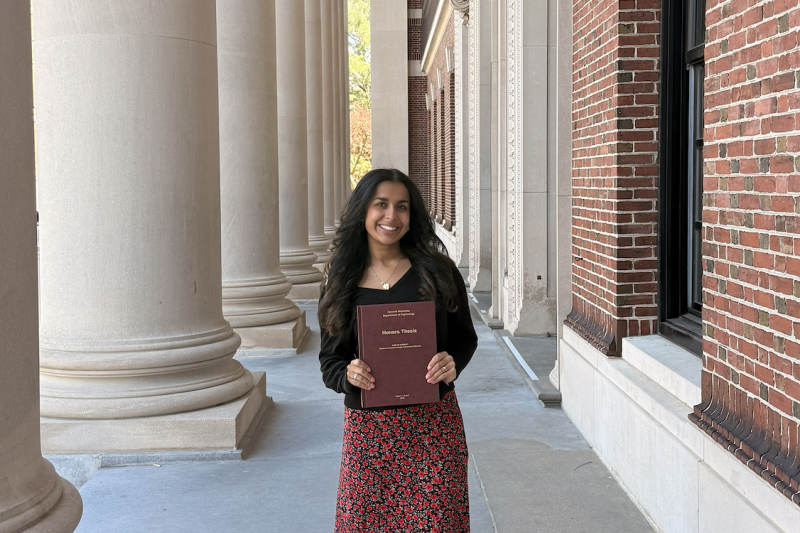 Gauri Sood '26 standing with her thesis papers in her hands.