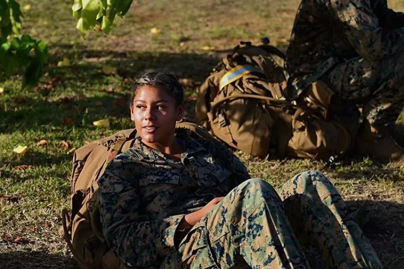 Vanessa Valverde '27 dressed in her uniform, sitting on the ground and staring off into the distance, during her time serving in the Marine Corps.