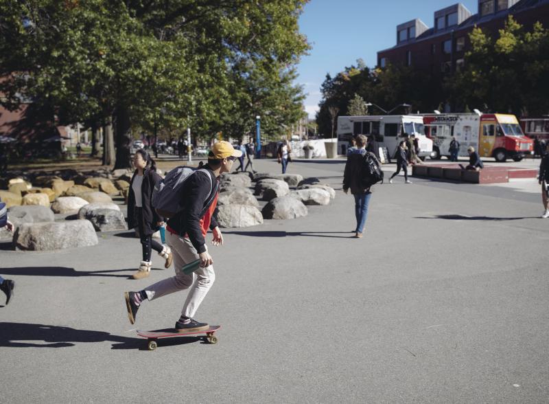 A student skateboarding across the Science Center Plaza