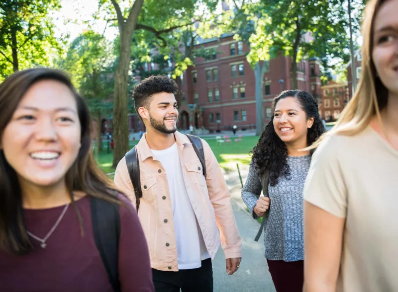 Four students smiling and walking through campus