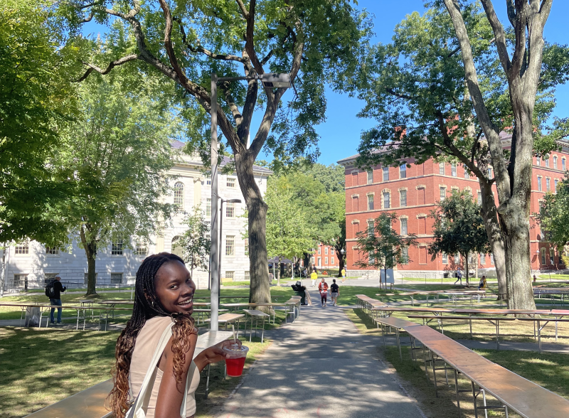 Author walking through Harvard Yard with hibiscus drink, smiling. 