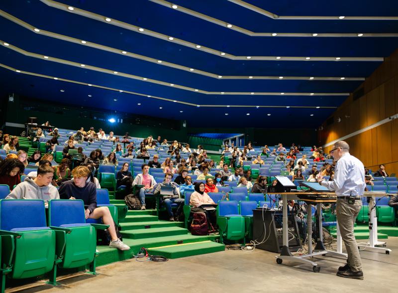 A professor giving a lecture to a auditorium full of students