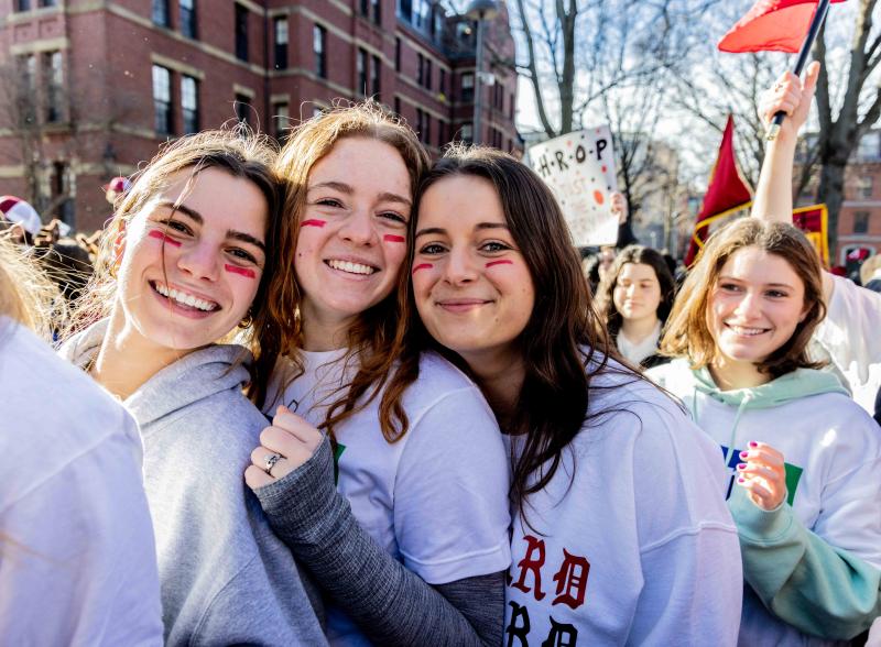 Smiling students standing in a crowd in Harvard Yard.