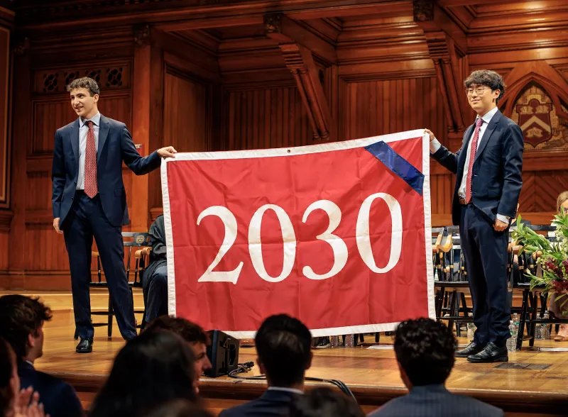 Zach Berg '28 and Daniel Zhao '28 holding up the Class of 2030 banner onstage.