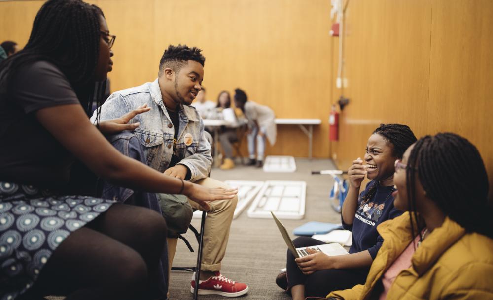 A group of students exchange smiles during a break in choral practice