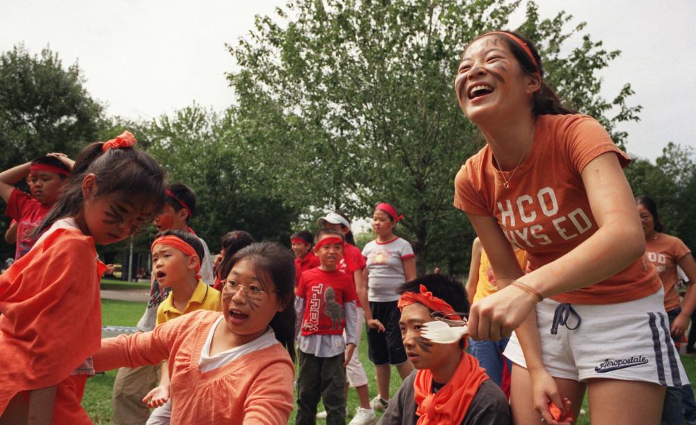 Students performing public service. One student with a group of children outside