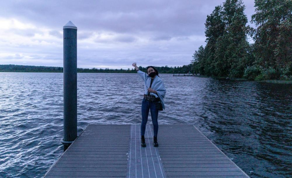 I am posing happily by a lake in my hometown near Seattle, WA. It's really cloudy and getting dark. 