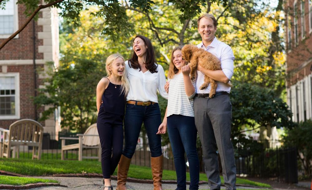 A portrait of Janine Santimauro and David Deming, faculty deans of Kirkland House, with their two daughters and dog.