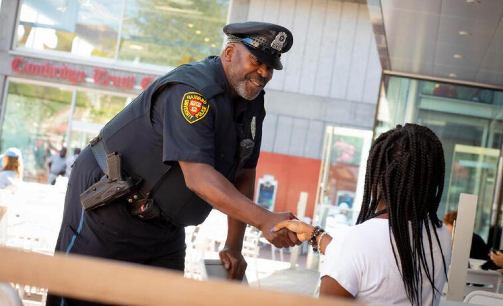 Harvard University Police officer shaking hands with a student outside