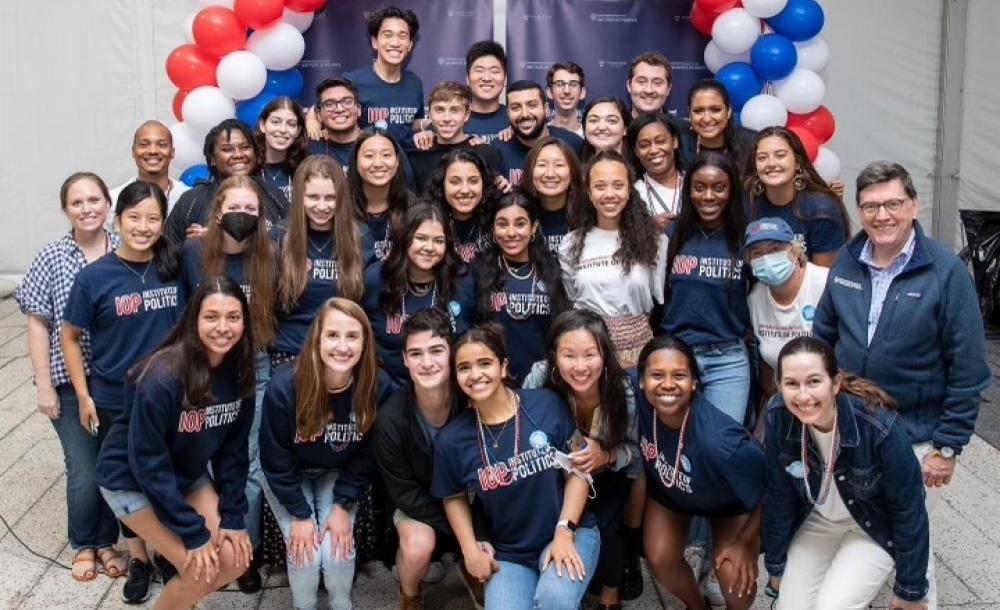 group of students in matching IOP t-shirts in front of red, white, and blue balloons