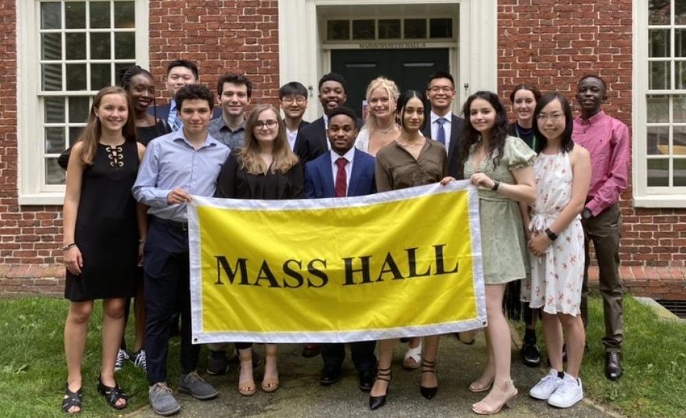 A picture of Mass Hall residents holding a yellow "Mass Hall" banner.